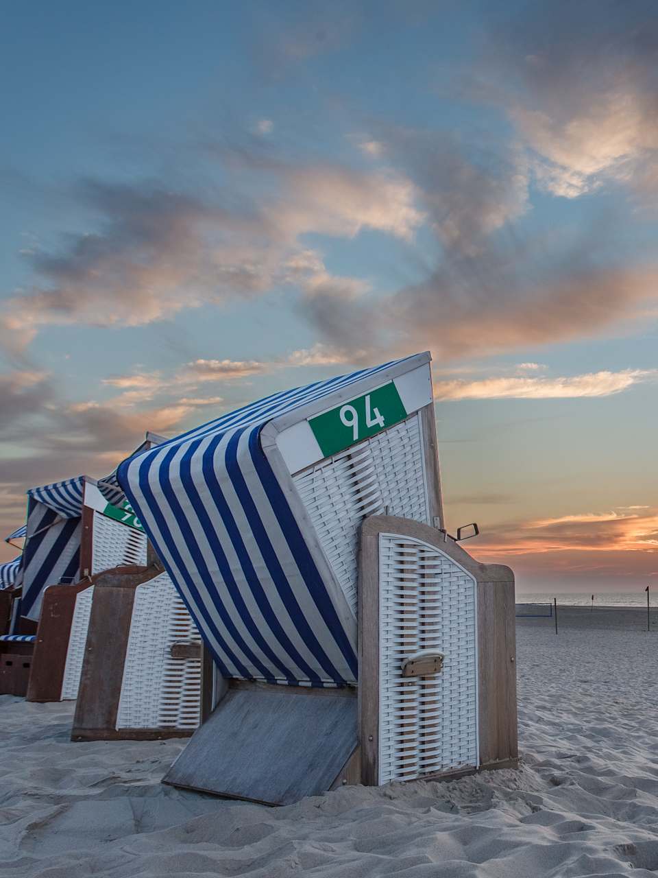 Strandkörbe an einem Strand bei Sonnenuntergang